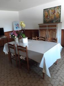 a table and chairs with a white table and flowers on it at La Ferme Du Marronnier in Valence-dʼAlbigeois