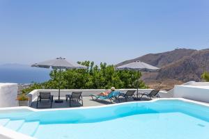 a person sitting in chairs next to a swimming pool at Loft Kaves Pool & Bar Suites in Pyrgos