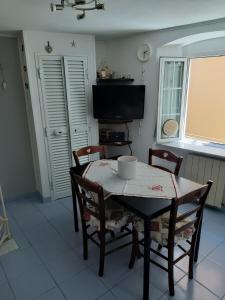 a dining room with a table and chairs and a television at Casa Ida in Montemarcello