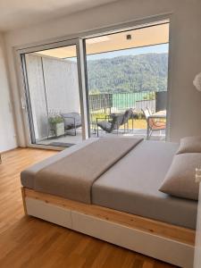 a bedroom with a large bed and a balcony at Lakeside Garden Ossiacher See in Sattendorf