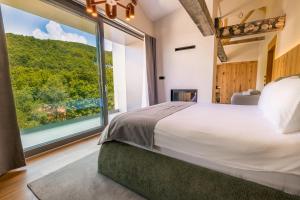 ein Schlafzimmer mit einem großen Bett und einem großen Fenster in der Unterkunft Pine Hotel & Spa Brezovice in Brezovica + 50 Fotos