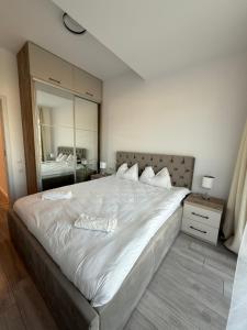 a large white bed in a bedroom with a mirror at Urban Nest Florești in Floreşti
