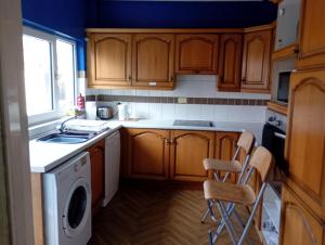 a kitchen with wooden cabinets and a washing machine at House near beach in Port Talbot +11 photos