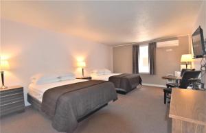 a hotel room with two beds and a desk at Willowbend Hotel in Maple Creek