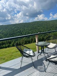 a patio with two chairs and a table on a deck at Crow`s Nest Murmur Măguri in Măguri