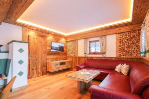 a living room with a red couch and a table at Chalet am Müllergut in Sankt Martin bei Lofer