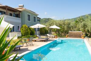 a pool with chairs and umbrellas next to a house at Golden Sun Bungalows in Palaiokatoúna