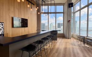 a bar with stools in a room with large windows at CD1608 Downtown Loft with Pool a Gym and City Views in Miami in Miami