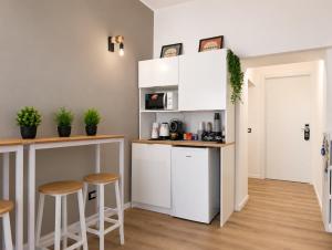 a kitchen with white cabinets and bar stools at Konero Room in Loreto