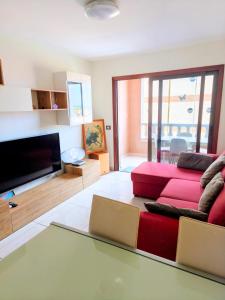 a living room with a red couch and a flat screen tv at La Ola in El Médano