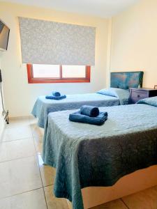 a room with two beds with blue towels on them at La Ola in El Médano