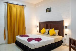 a bedroom with a large bed with yellow curtains at Roy's Polonnaruwa in Polonnaruwa +11 photos