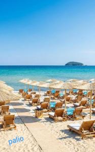 a beach with chairs and umbrellas and the ocean at SUNRISE LUXURY POOL VILLA in Paleo Tsifliki
