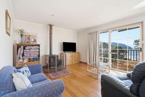a living room with a blue couch and a television at Eaglehawk Neck Getaway in Eaglehawk Neck