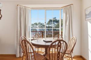 a dining room with a table and chairs and a large window at Eaglehawk Neck Getaway in Eaglehawk Neck