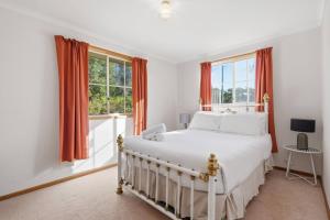a bedroom with a white bed and two windows at Eaglehawk Neck Getaway in Eaglehawk Neck