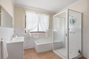 a white bathroom with a shower and a tub and a sink at Eaglehawk Neck Getaway in Eaglehawk Neck +37 photos