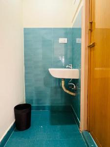a bathroom with a sink and a blue tiled wall at Green Hills Cottage in Aravankādu