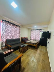 a living room with a couch and a tv at Green Hills Cottage in Aravankādu +14 photos