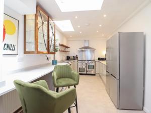 a kitchen with two green chairs and a refrigerator at Sea View, East Parade in Llandudno