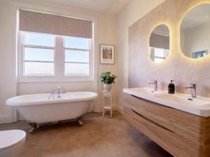 a bathroom with two sinks and a tub and a toilet at Sea View, East Parade in Llandudno +57 photos