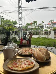 two pizzas and bread sitting on a table at Captain's Home Phong Nha in Phong Nha