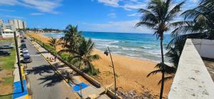 a view of a beach with palm trees and the ocean at Oceanfront 3-bedroom Sub-Penthouse in Luquillo PR in Luquillo