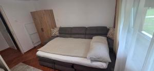 a bed in a room with a brown leather couch at Melody Apartment Kutina in Kutina +16 photos