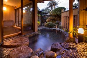 a lap pool in a backyard with rocks and a house at Charoku Bekkan in Miyazu +74 photos