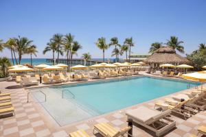 a swimming pool with lounge chairs and umbrellas at The Sunny in Sunny Isles Beach