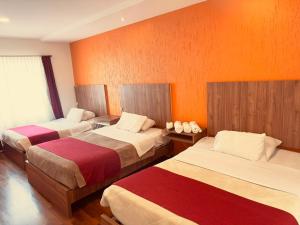two beds in a room with orange walls at Hostal NIZZA in Cuenca