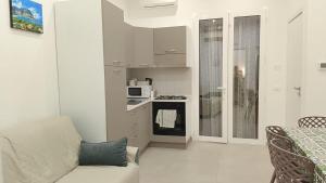 a white kitchen with a couch and a microwave at House Mare Blu in Balestrate
