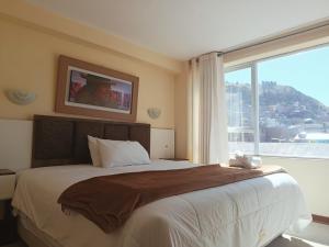 a bedroom with a large bed with a large window at Kaaro Hotel Suite in Puno