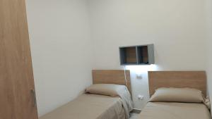 a room with two beds and a tv on the wall at House Mare Blu in Balestrate
