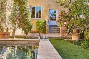 a house with a bottle of wine next to a swimming pool at Maison d'hôtes de charme Le Clos de la Cathédrale en Sud Gironde in Bazas