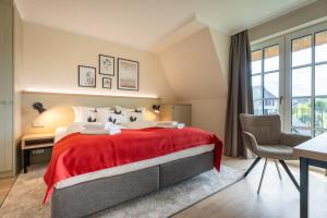 a bedroom with a large bed with a red blanket at Apartmenthaus Resort Kranichsruh in Fuhlendorf