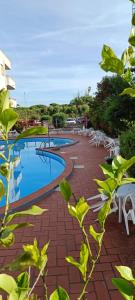a swimming pool with white chairs and tables at C e G House in Santa Marinella
