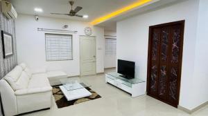 a living room with a couch and a tv at Blue Breeze Villa in Mahabalipuram +11 photos
