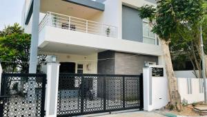 a white house with a black gate and a tree at Blue Breeze Villa in Mahabalipuram