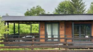 a wooden cabin with a fence in front of it at House Riverside in Kozmacz