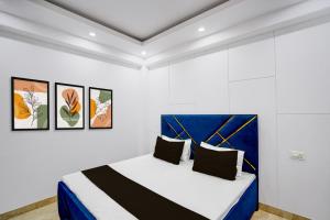 a white room with a bed with a blue headboard at Hotel O Maxico in New Delhi