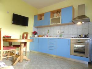 eine Küche mit blauen Schränken, einem Tisch und einem TV in der Unterkunft Apartments Vrša in Seline + 37 Fotos