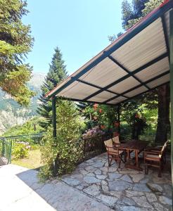 a patio with a wooden table and chairs under awning at Mountain Nook Melissourgoi in Melissourgoí