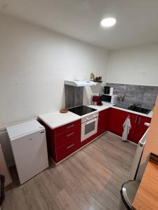 a small kitchen with red cabinets and a white refrigerator at Écrin de barr in Barr