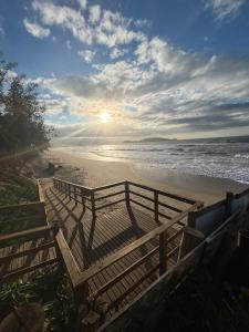 a row of benches on a beach with the ocean at Graffi Beach House in Florianópolis