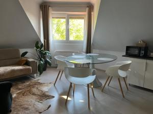 a living room with a glass table and white chairs at Studio Strasbourg in Niederhausbergen +9 photos