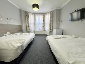 a room with two beds and a large window at Plaza Hotel in London
