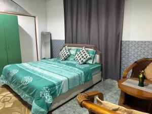 a bedroom with a green bed with pillows on it at Simple Beach Stay 100m to Dahariz Beach Salalah in Salalah