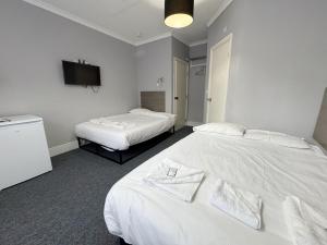 a hotel room with two beds and a flat screen tv at Plaza Hotel in London