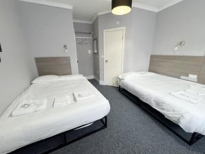 two beds in a hotel room with white sheets at Plaza Hotel in London